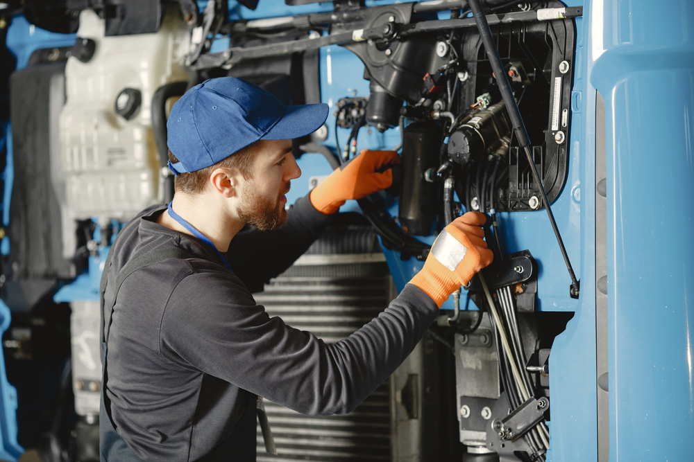 Image a man wearing a blue hat fixing truck issues