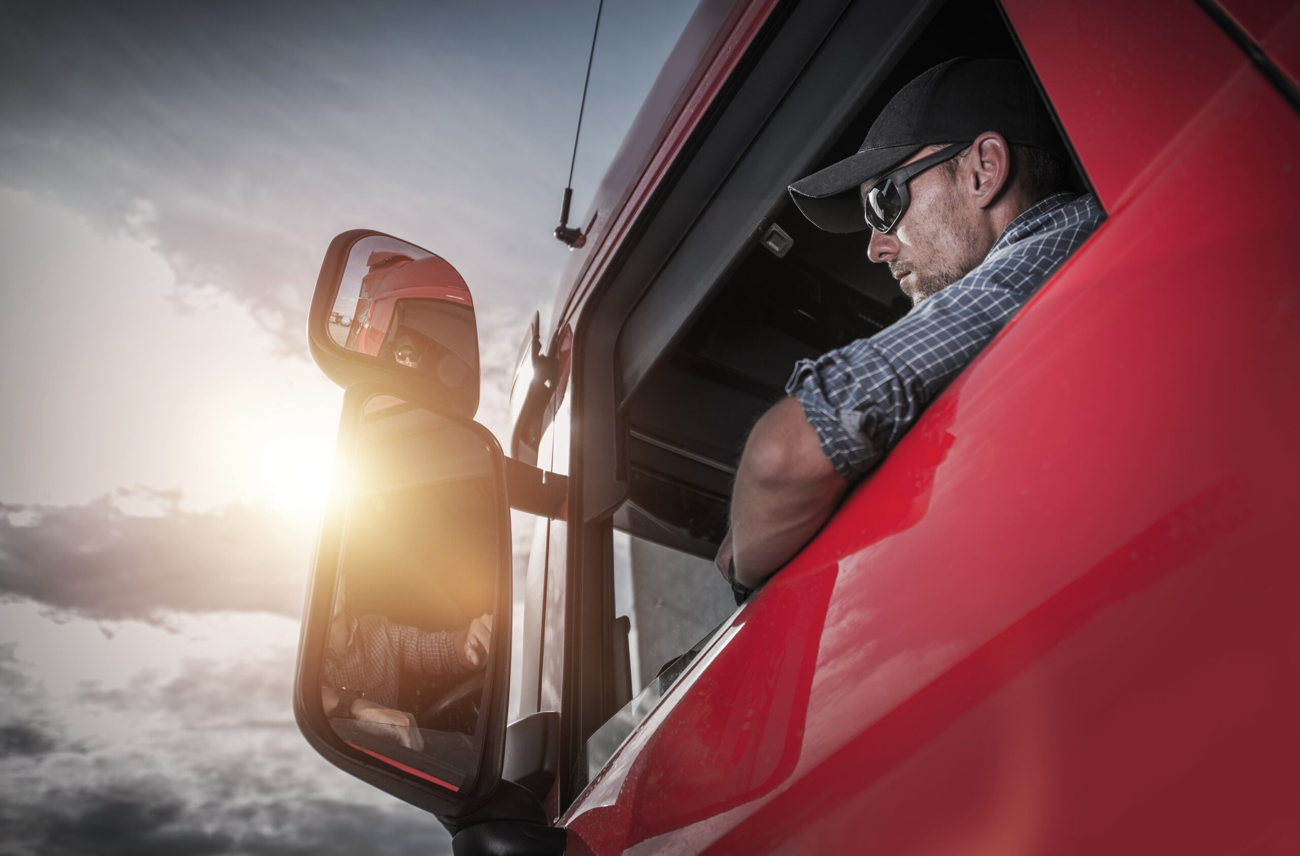 Image of a man wearing a hat and glasses inside of his truck for truck maintenance
